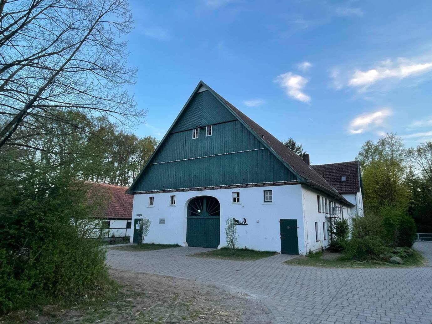 Altes Bauernhaus im Grünen vor blauem Himmel.