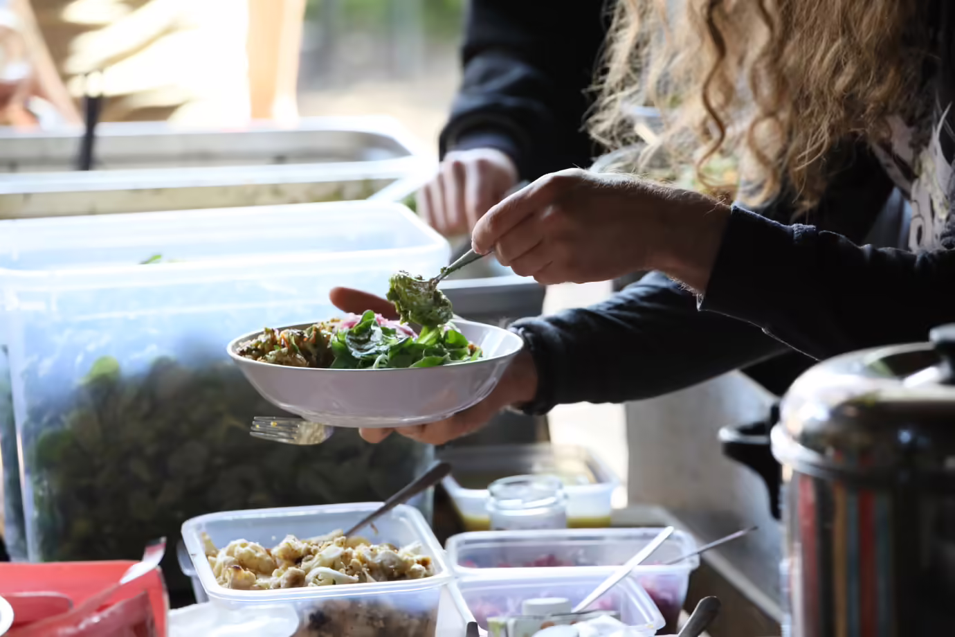 Person serviert Salat aus Buffet.