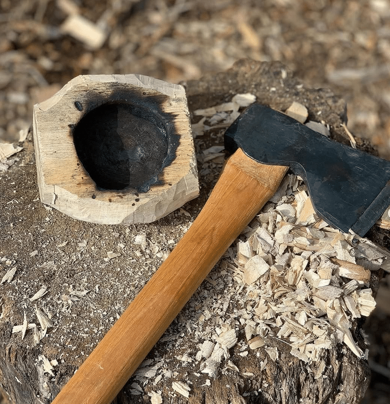 Holz mit Axt und Schnitzspänen auf Baumstumpf.
