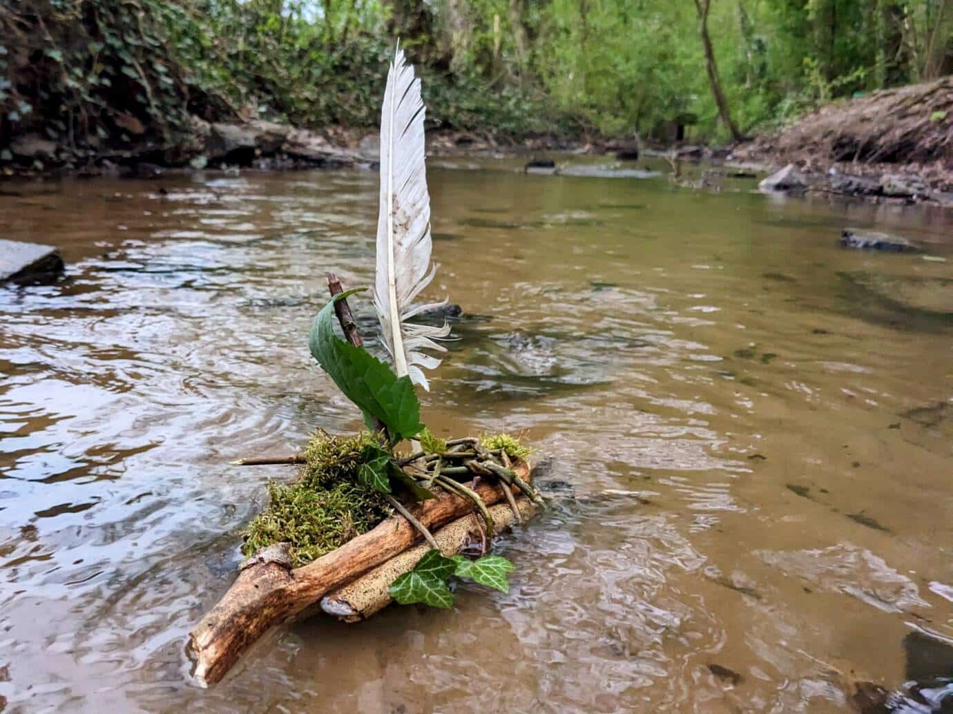 Floß aus Stöcken und Blättern im Bach