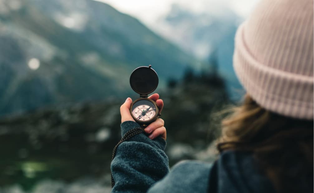 Person hält Kompass in den Bergen